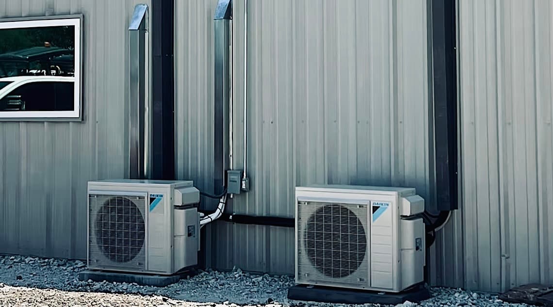 A row of wall-mounted Daikin condensing units on a commercial metal building