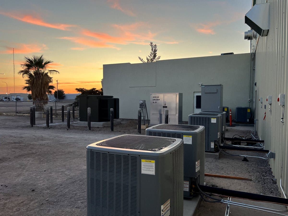 Ground-mounted condensers outside a commercial building at sunset