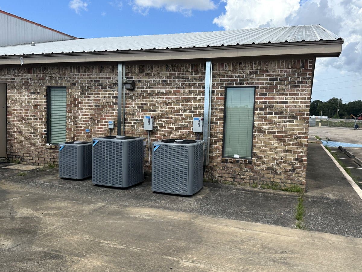 Condensers on a pad beside a brick commercial building